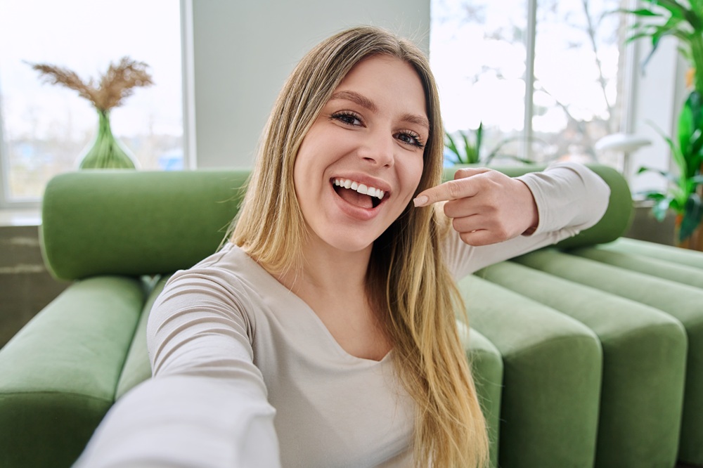 Woman taking a selfie while pointing to her bright, white smile