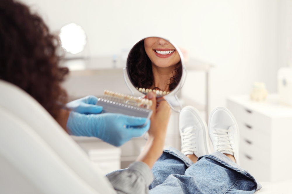  Patient comparing tooth shades in a hand mirror during a teeth whitening consultation