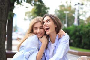 Two friends in matching blue shirts laughing together outdoors